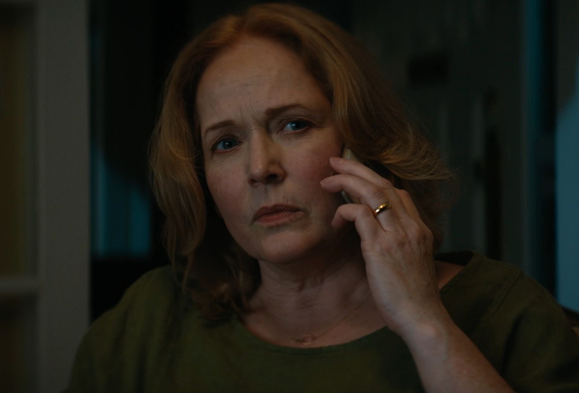 Person with shoulder-length hair holds a phone to their ear, looking concerned