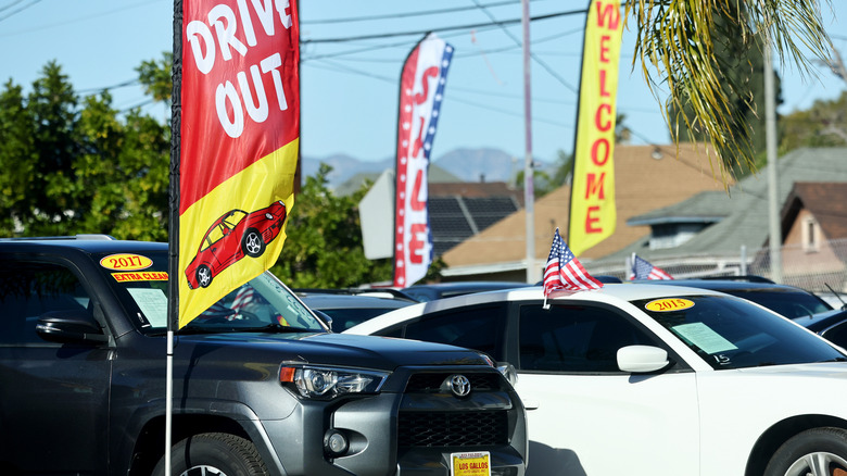 Stajalište rabljenih automobila s rabljenom sivom Toyotom 4-Runner, bijelim Dodge Chargerom i drugim vozilima.