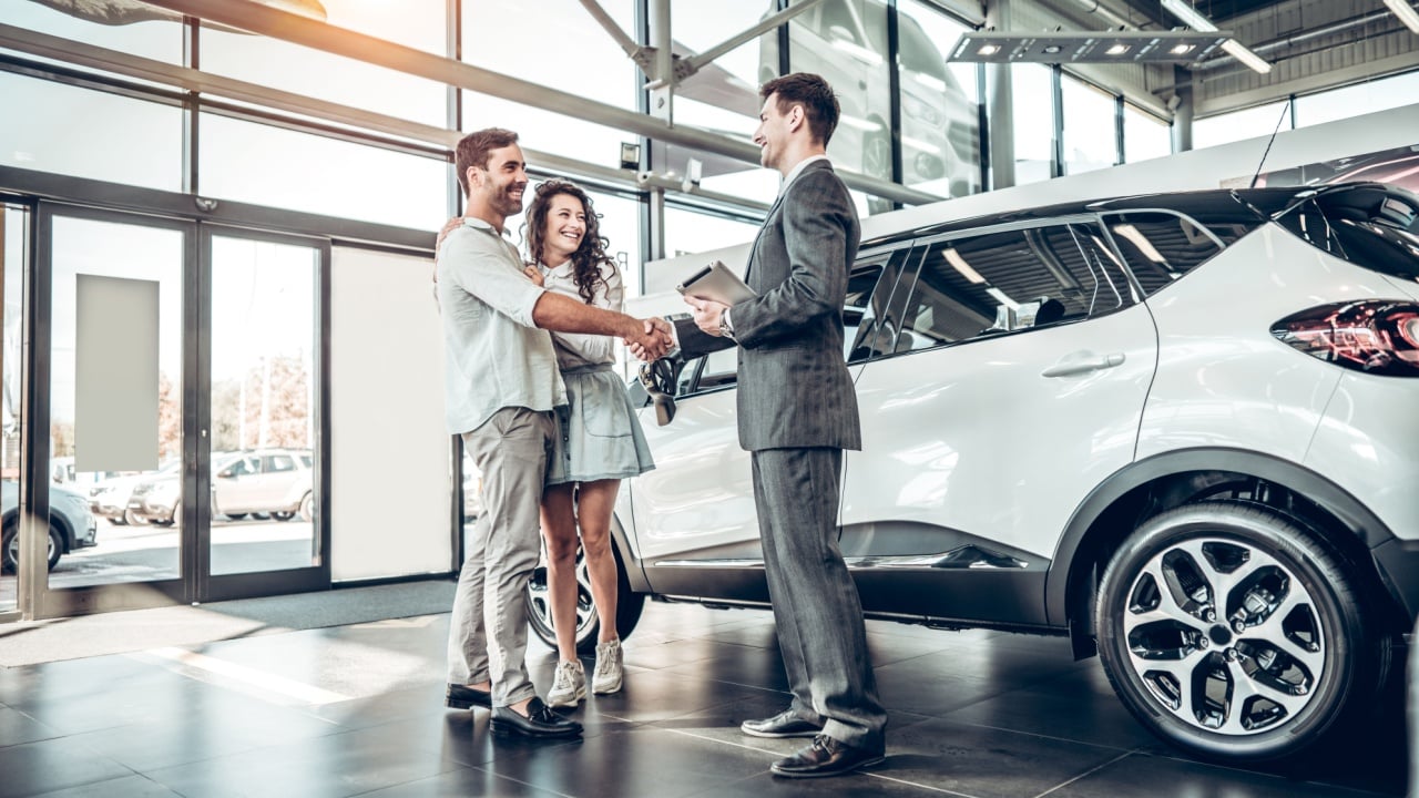 Mladi par rukuje se s prodajnim agentom nakon kupnje automobila