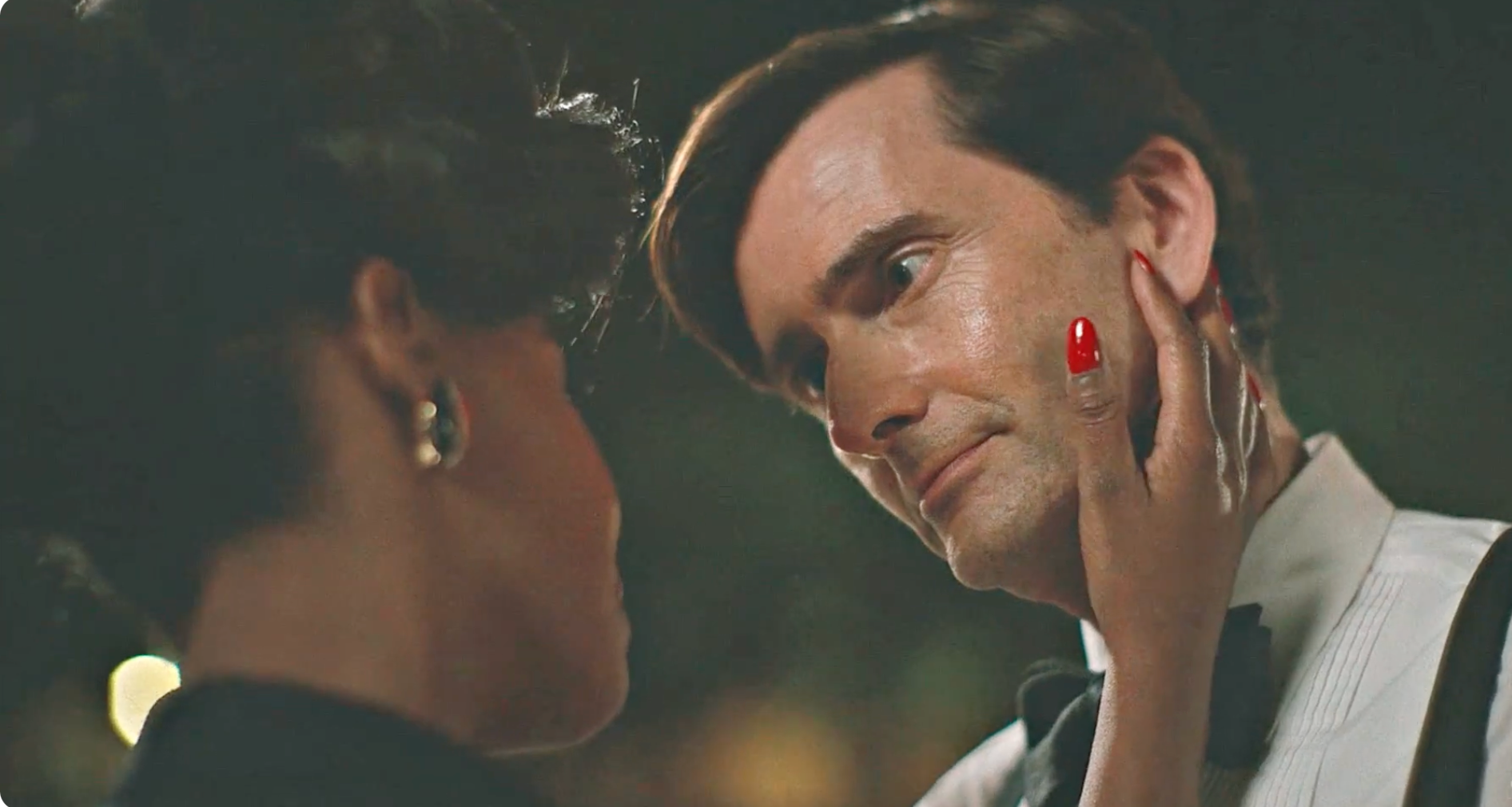 David Tennant, in formal wear, gazes intently at a woman touching his face
