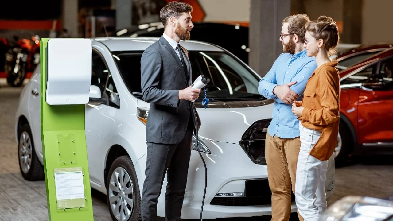 električno vozilo u autosalonu, stanica za punjenje EV vozila, prodaja električnih automobila, par kupuje automobil