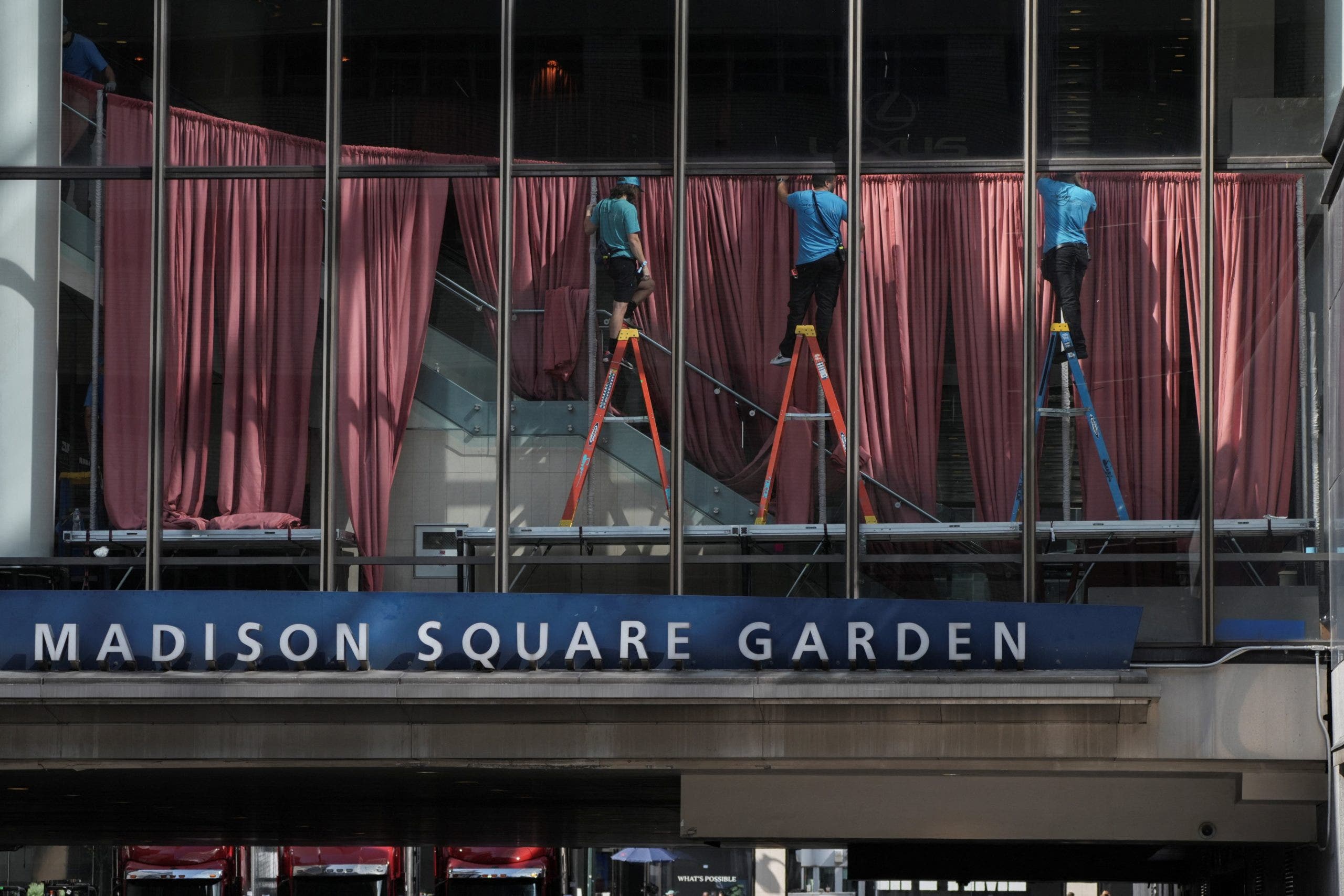 Workers hang up red curtains to block the windows at Madison Square Garden ahead of Taylor Swift and Travis Kelce's rumored wedding