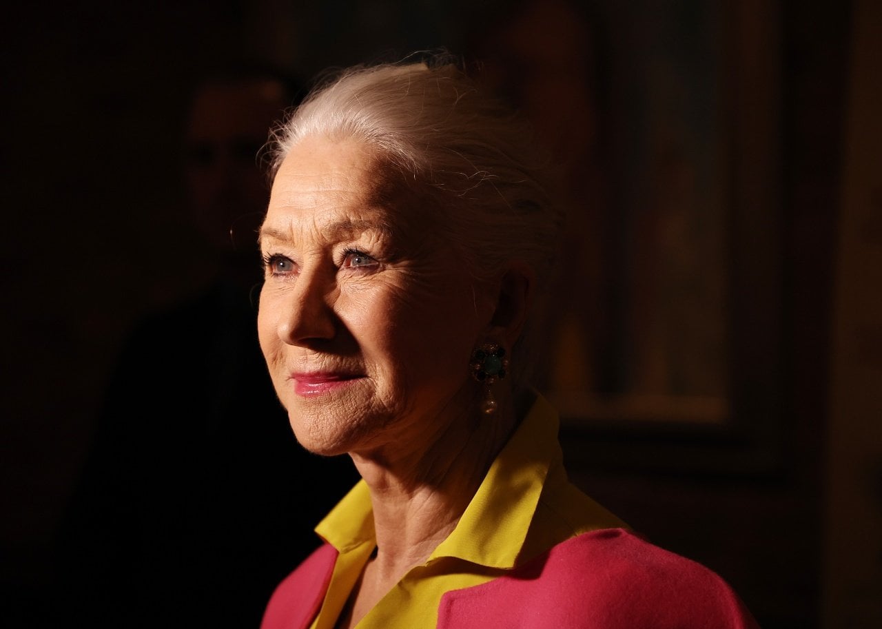Helen Mirren in pink and yellow looking up with light on her face. - 
