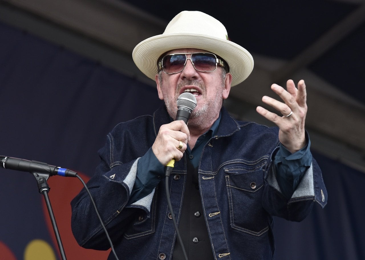 Elvis Costello performs in a dark denim jacket, hat and sunglasses. - 