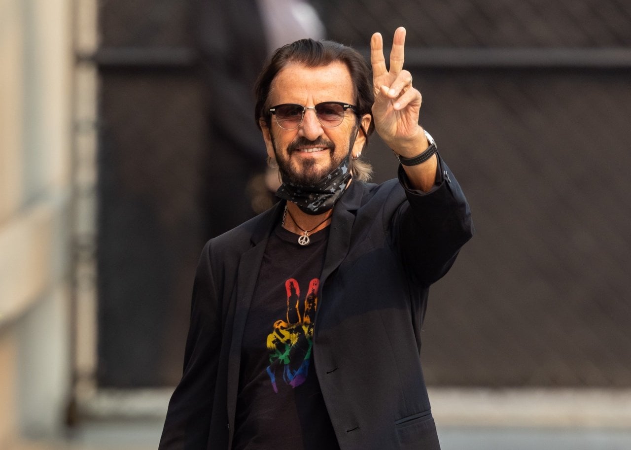 Ringo Starr flashes the peace sign. - 