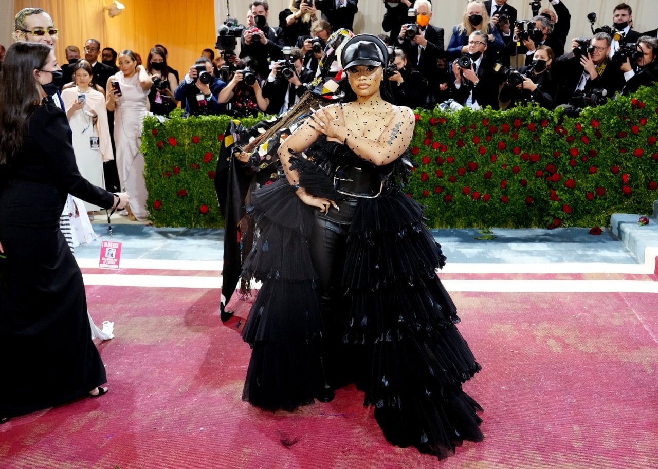 Nicki Minaj wearing a black ruffled tulle gown with a black leather body suit underneath and hat. - 