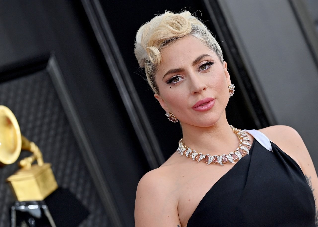 Lady Gaga in a one-shoulder black-and-white gown wearing gold jewelry and an updo. - 