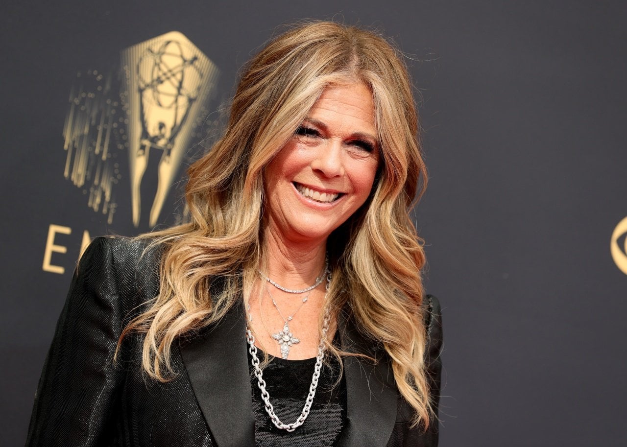 Rita Wilson smiles in front of a black background. - 