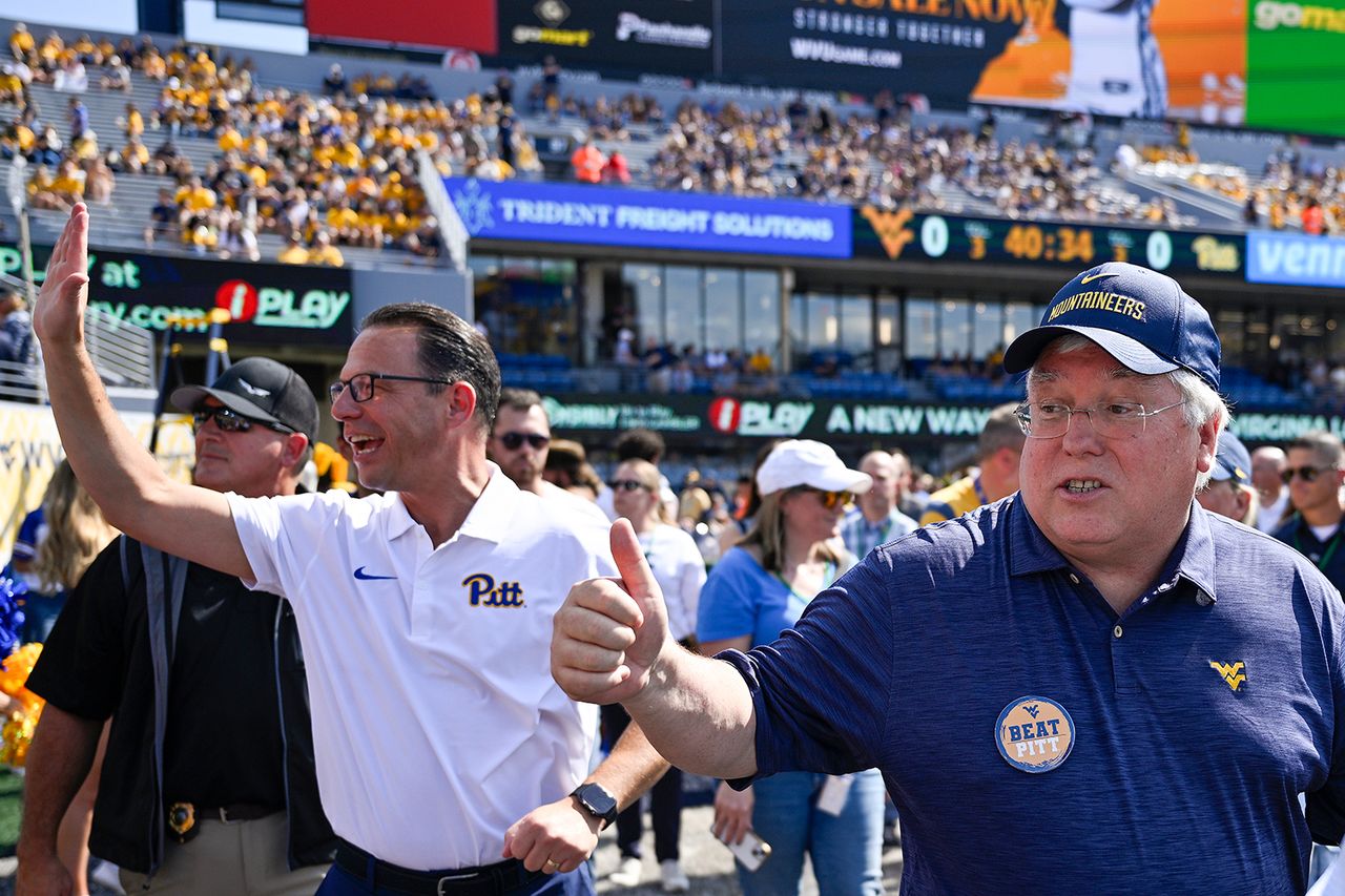 Pennsylvania Gov. Josh Shapiro and West Virginia Gov. Patrick Morrisey wave to fans before a game at Milan Puskar Stadium in Morgantown, W.Va., on Sept. 13, 2025Credit: Brien Aho/Getty