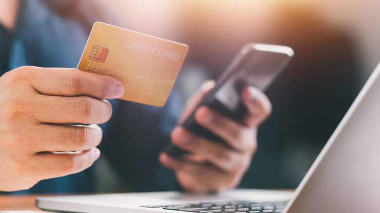 Close up of male hands holding credit card in one and a phone in the other