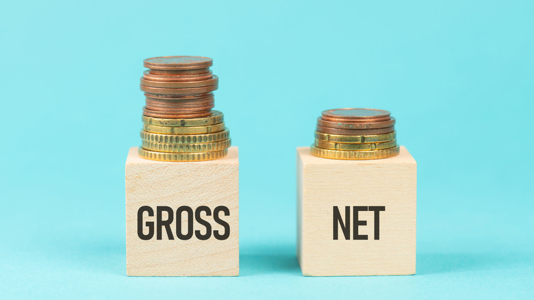 Two blocks with coin money, one with the word "gross" and the other with the word "net"