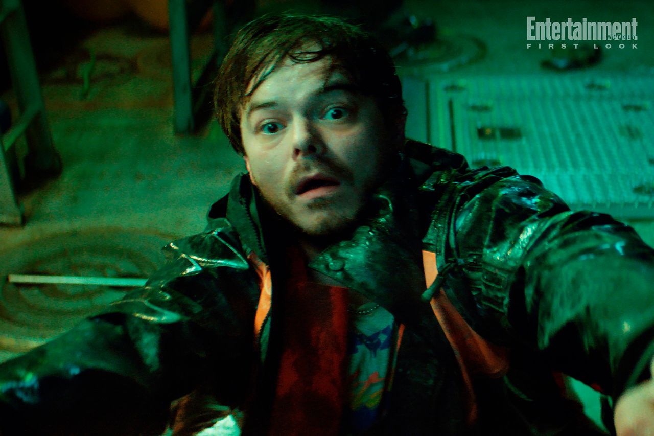 A frightened fisherman recoils in eerie green light in a promotional still from Below