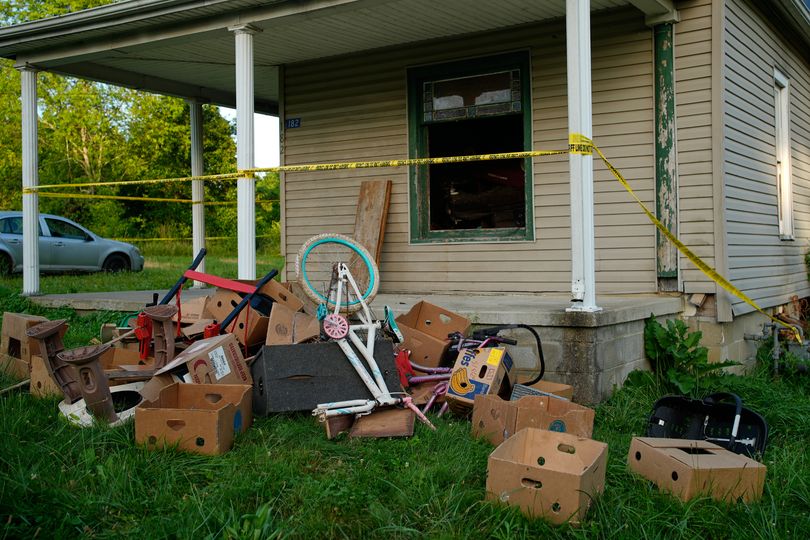 Police tape surrounds a home and debris is seen on the front lawn, including baby carrier, where authorities say they removed 16 children and arrested four adults in Hamden, Ohio, Wednesday, July 1, 2026.