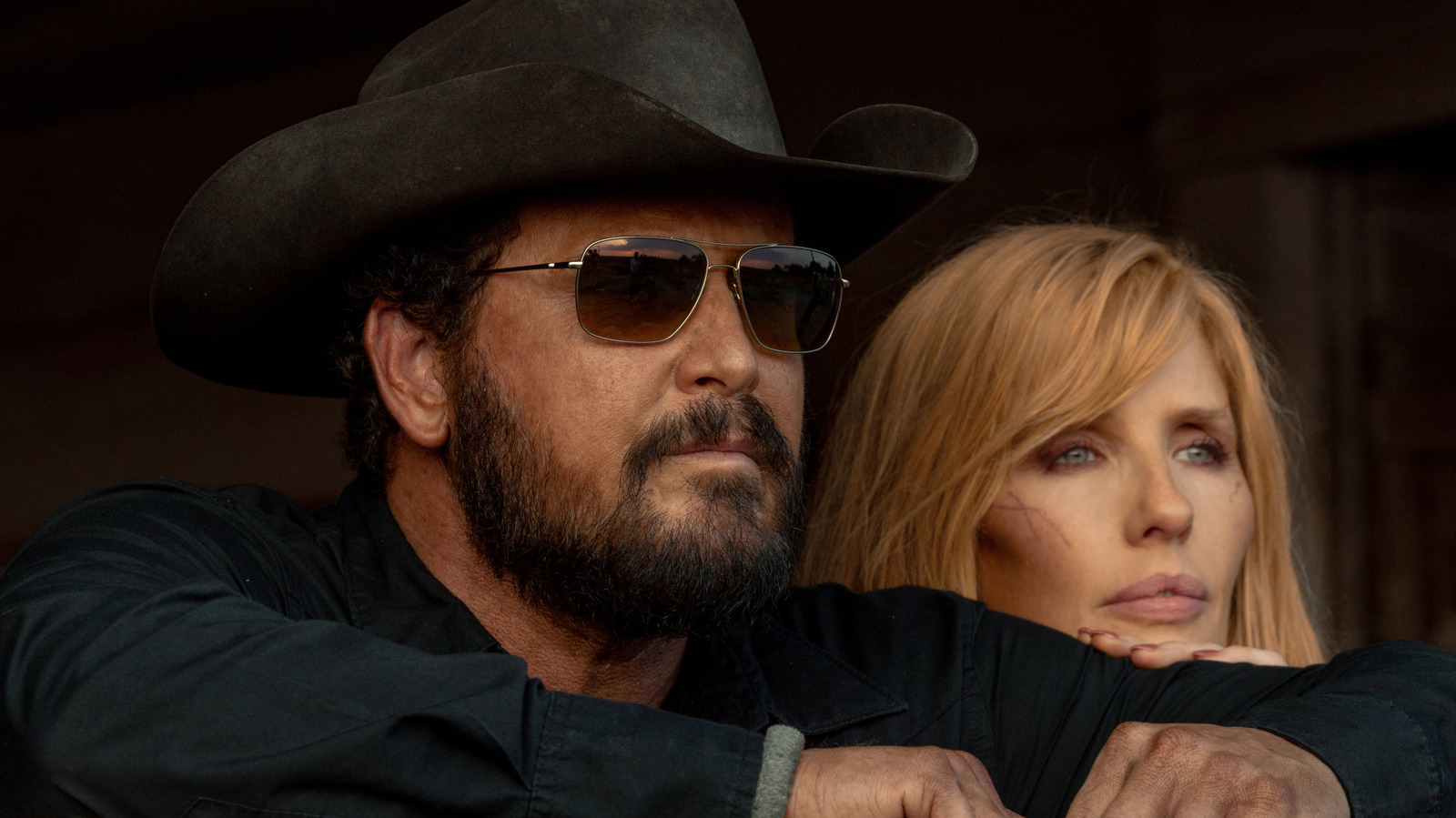 Cole Hauser's Rip Wheeler looks off into the distance wearing shades next to Kelly Reilly's Beth Dutton in Dutton Ranch