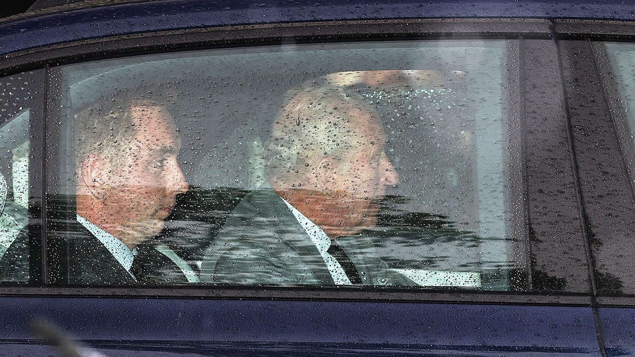 El rey Carlos dentro de un coche en un día lluvioso.