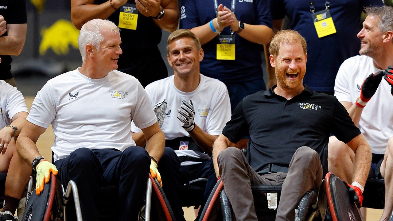 Al Carns y el príncipe Harry juegan al rugby en silla de ruedas en un gimnasio.