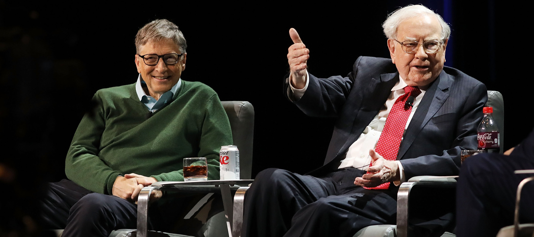 Bill Gates and Warren Buffett on stage together at a speaking event.