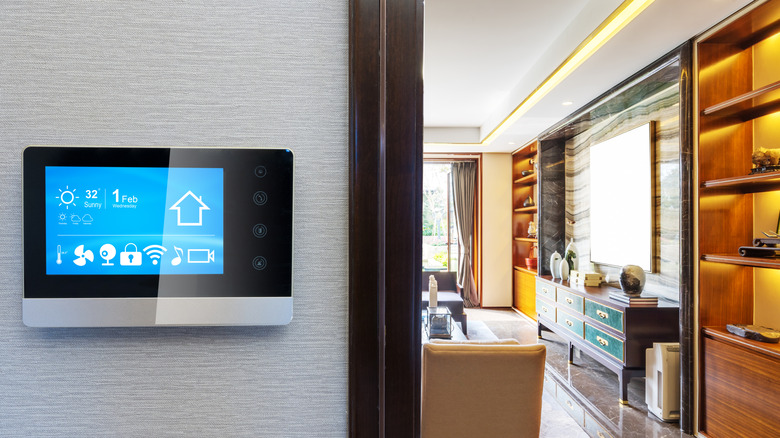 A digital smart thermostat placed on a wall of a house, with the kitchen in full view