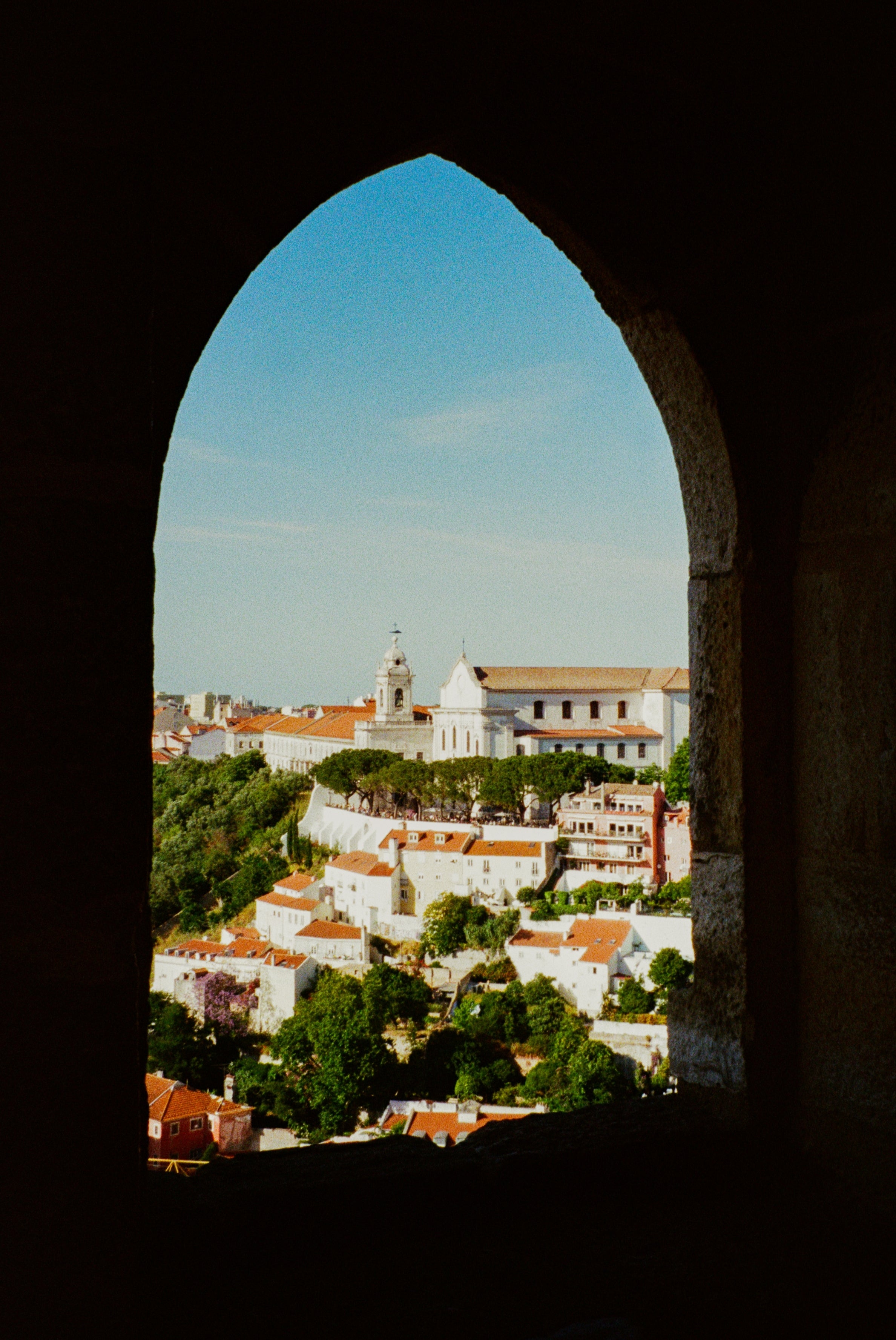 Vista de uma paisagem urbana histórica emoldurada por um arco, com telhados e uma igreja proeminente