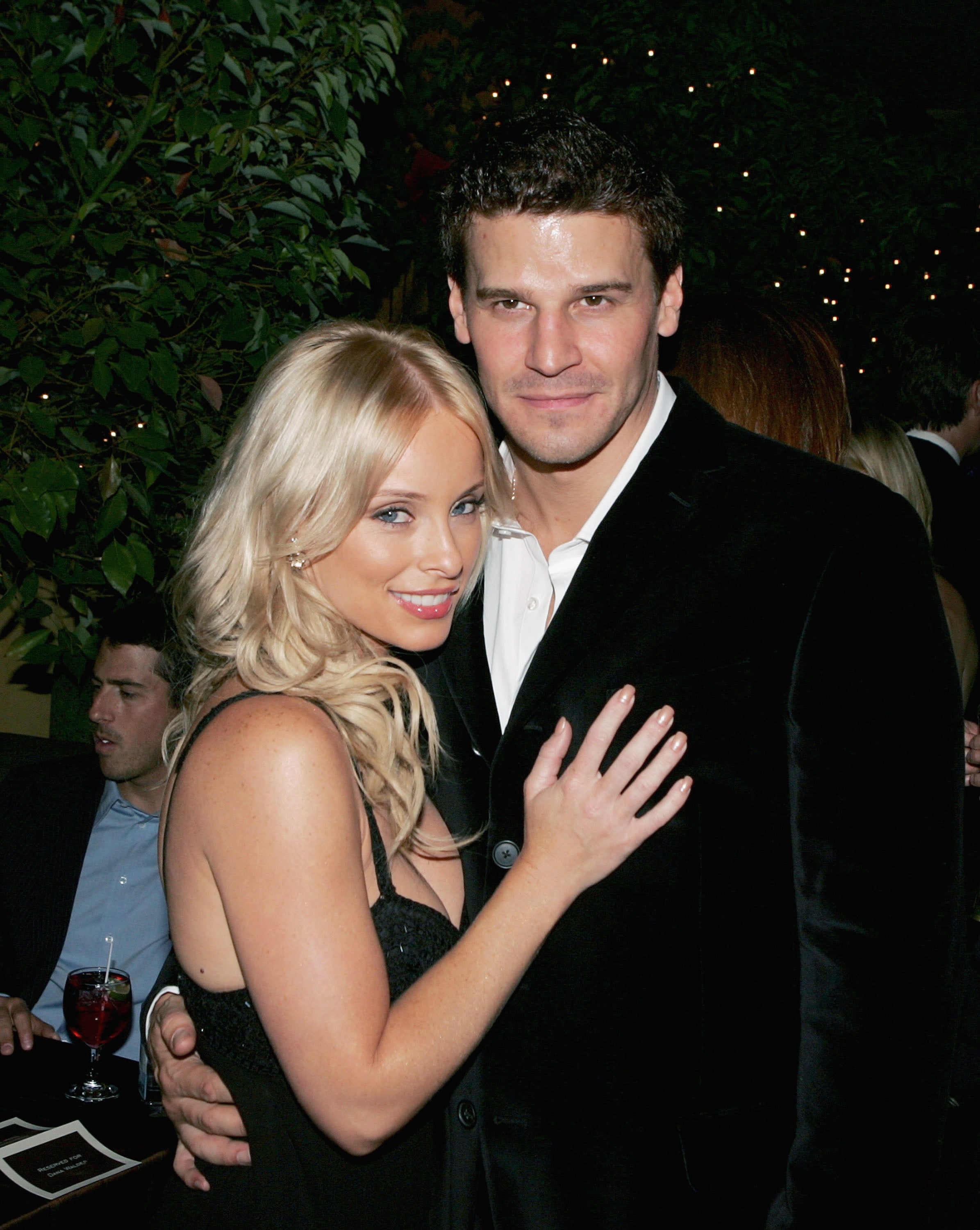 David Boreanaz wears a black blazer and a white button-up shirt while posing with his wife, Jamie Bergman, who wears a black dress