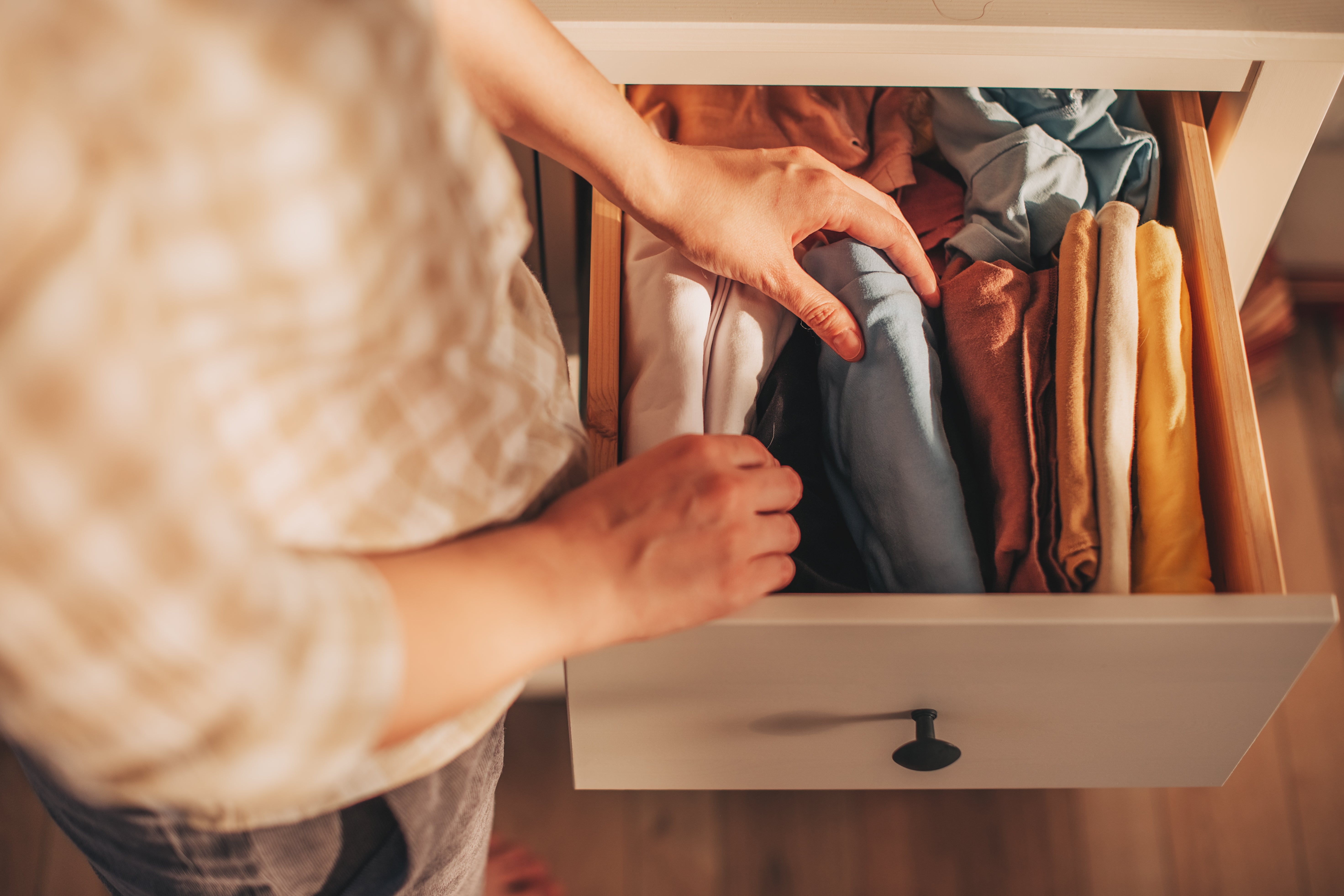 A person taking clothing out of a dresser drawer