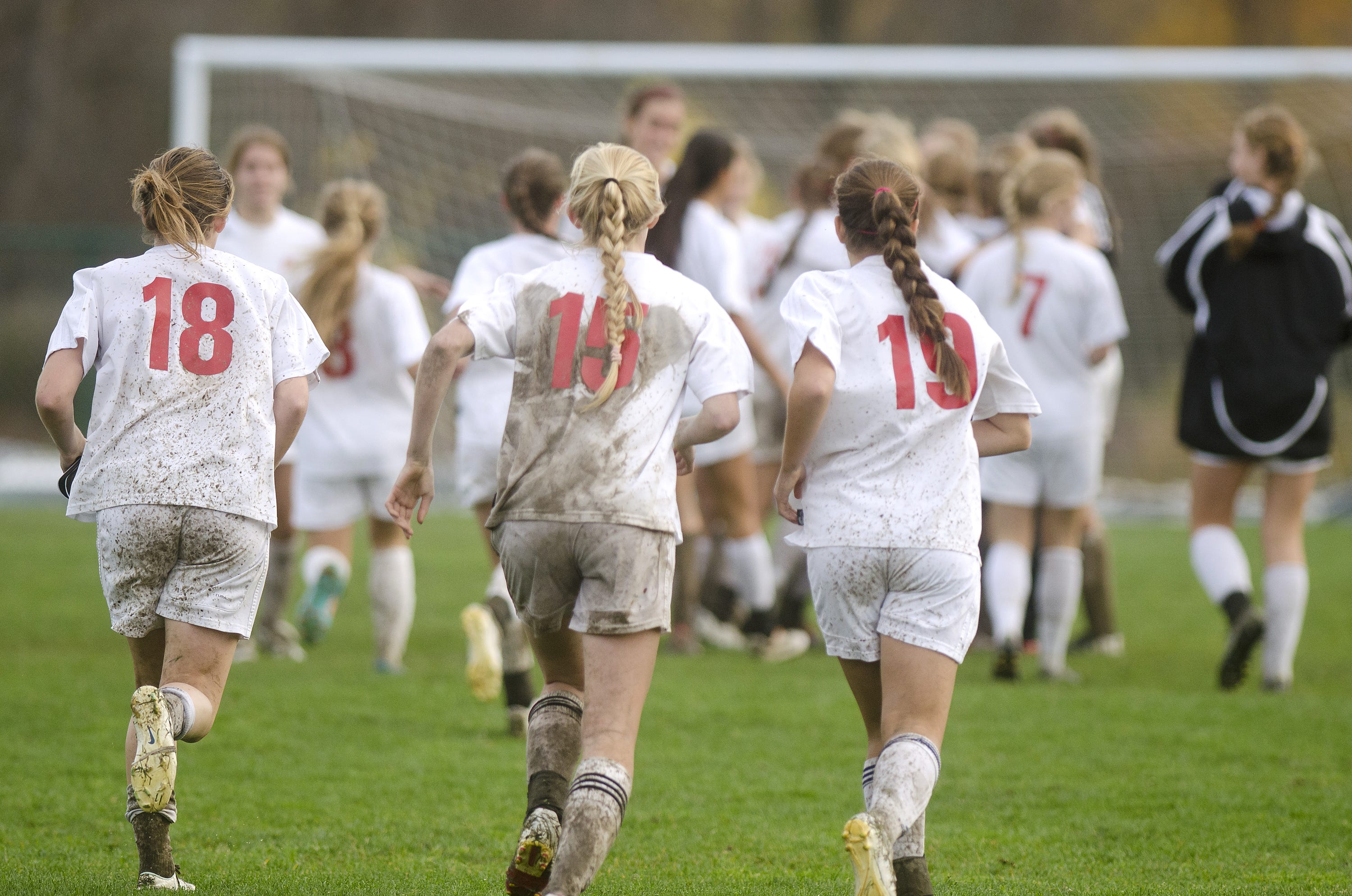 Champlain Valley's Megan Gannon (18), Sierra Morton (15) and Naomi Burhans run to celebrate with their team after the Redhawks 3-0 win over Colchester in the 2013 Division I girls soccer semifinals