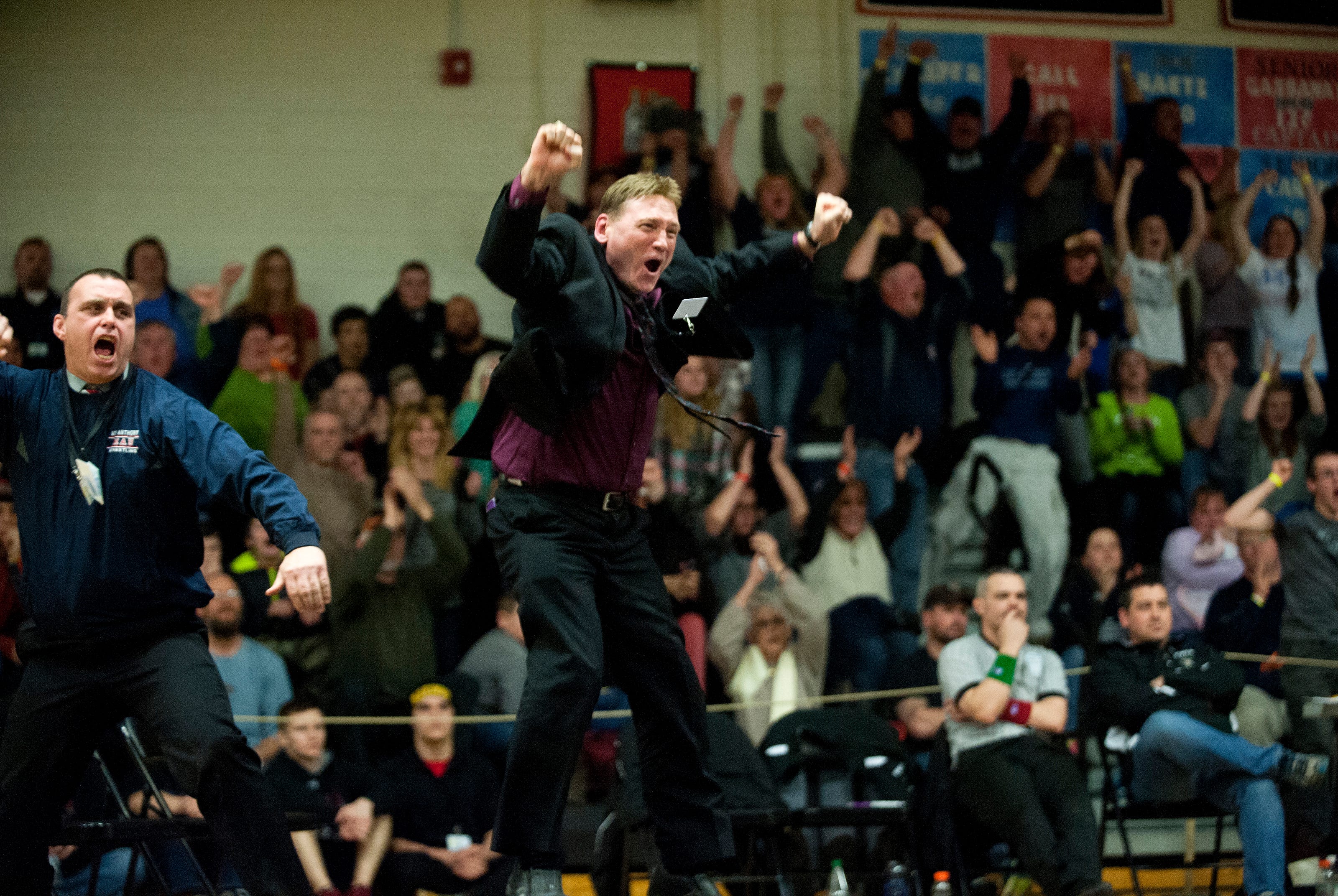 Mount Anthony coach Scott Legacy, center, celebrates after Ezra Caron's overtime victory in the 182-pound state championship match in Middlebury in 2015.