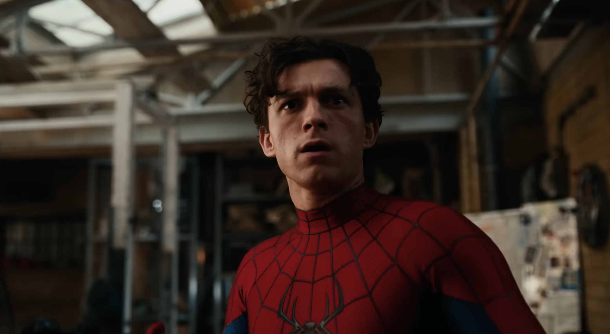 Tom Holland in a Spider-Man costume looks surprised in an industrial setting