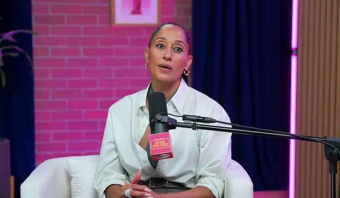 Persona sentada en un estudio, hablando por un micrófono etiquetado "Propiedad de una mujer negra."