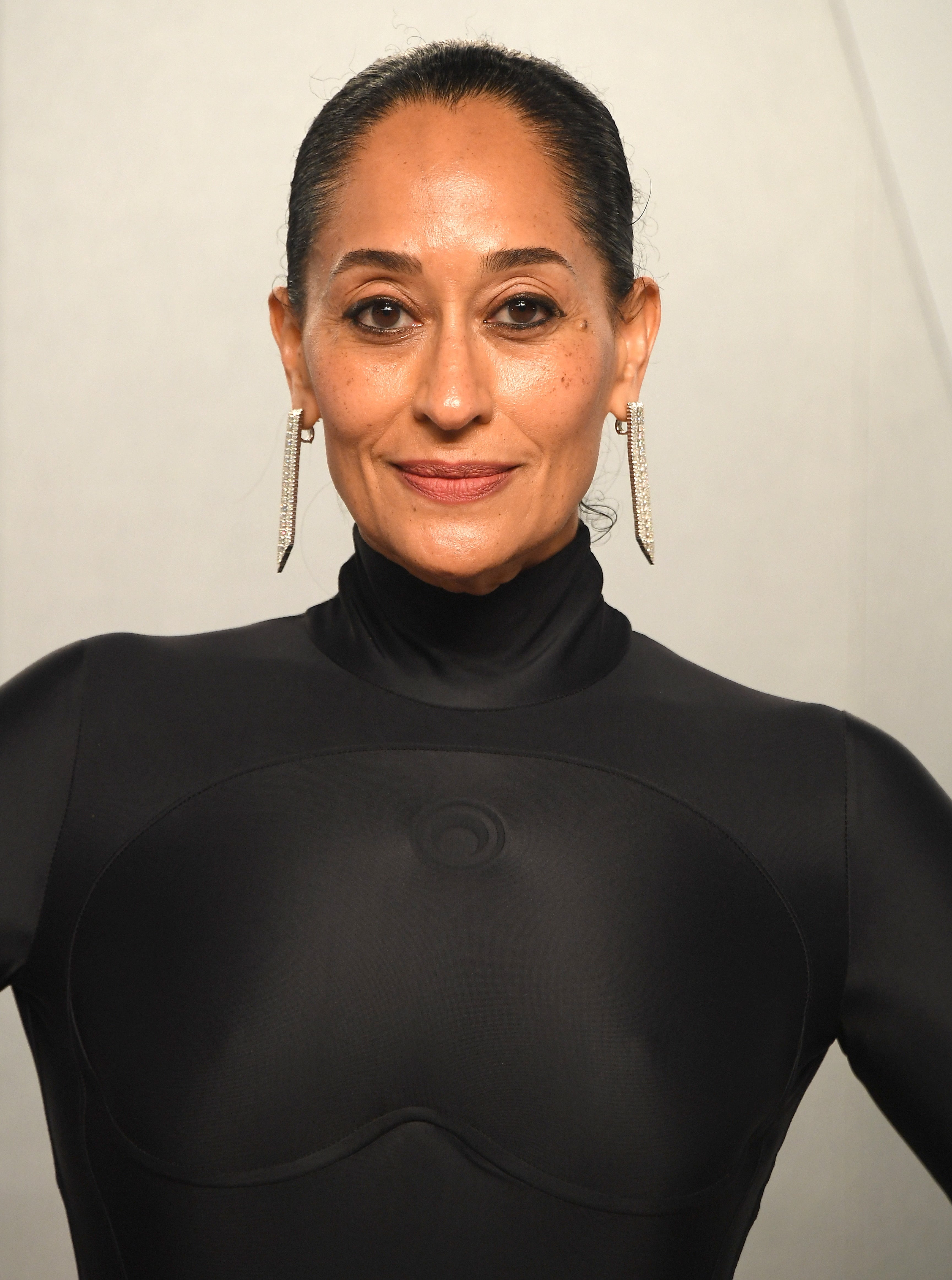 Persona con un traje negro elegante y ajustado con aretes grandes y brillantes, posando en un evento