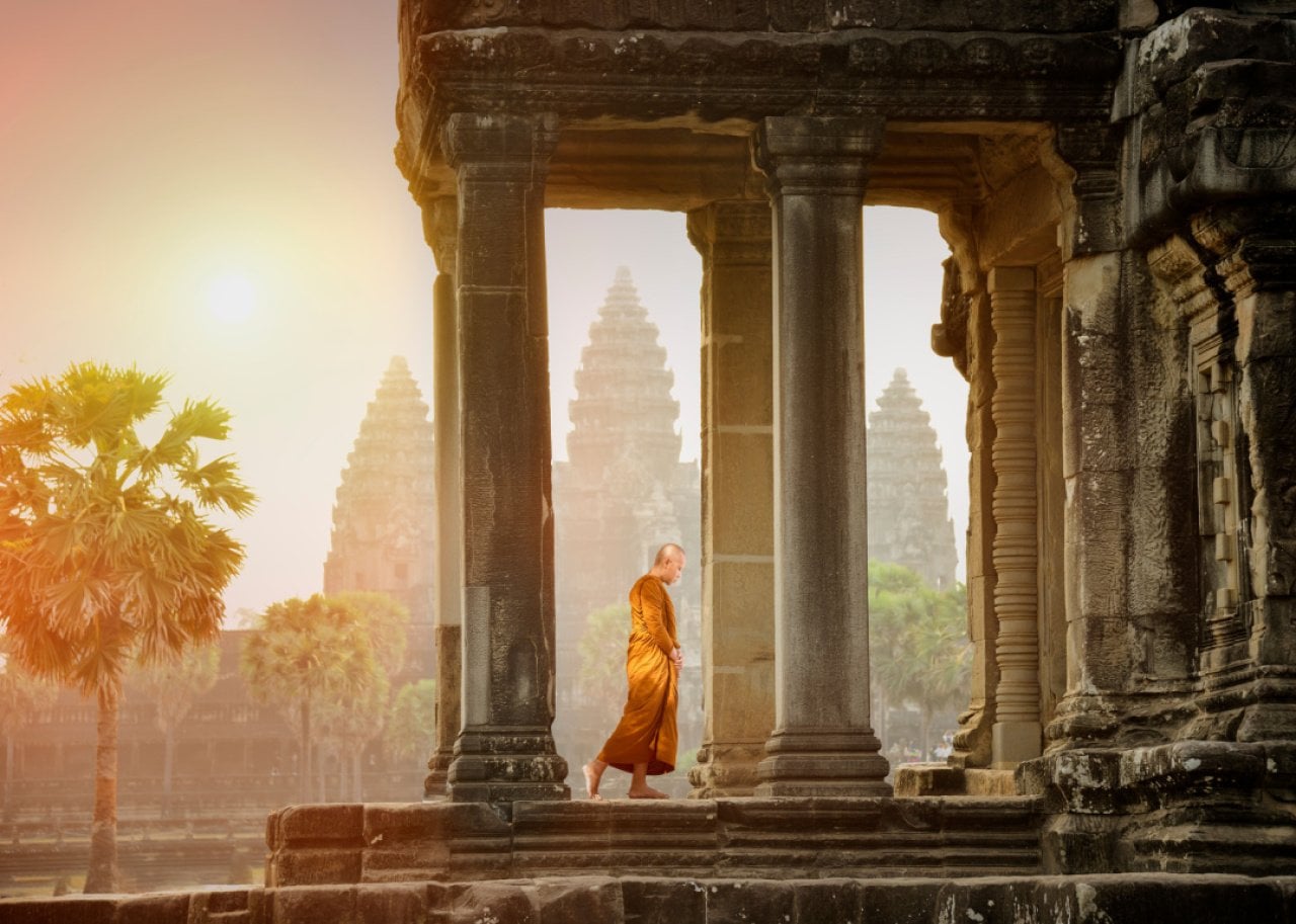 Monk walking in temple landscape at Angkor Wat. - 