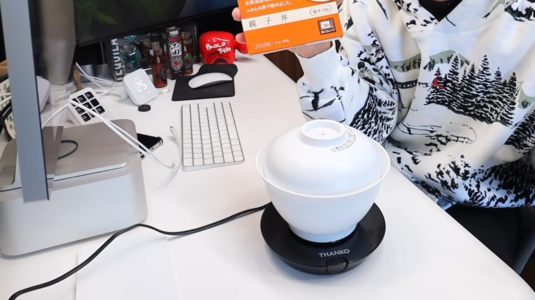 A small white rice cooker over a black heating element