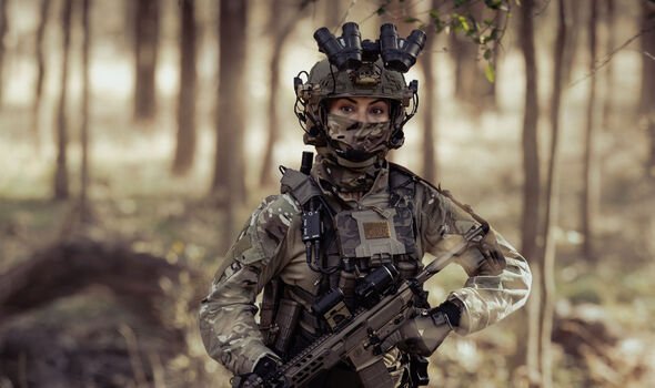 A solider in heavy armour walks with a gun