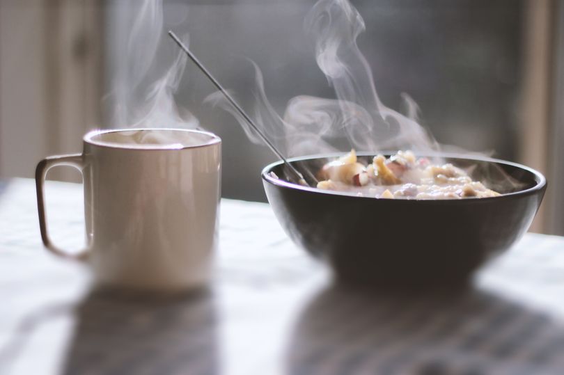 Close-up of porridge and tea served in a bowl on table with morning light and shadows coming through the window in the background.