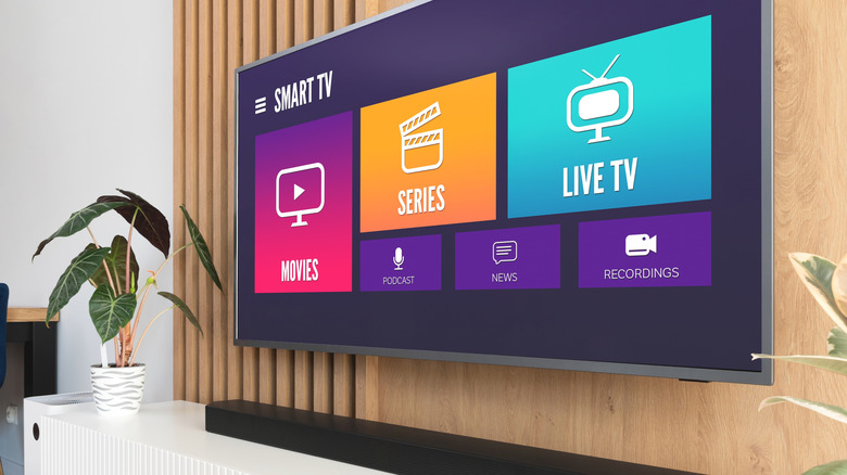 smart tv mounted on wooden wall with a soundbar and plant placed underneath
