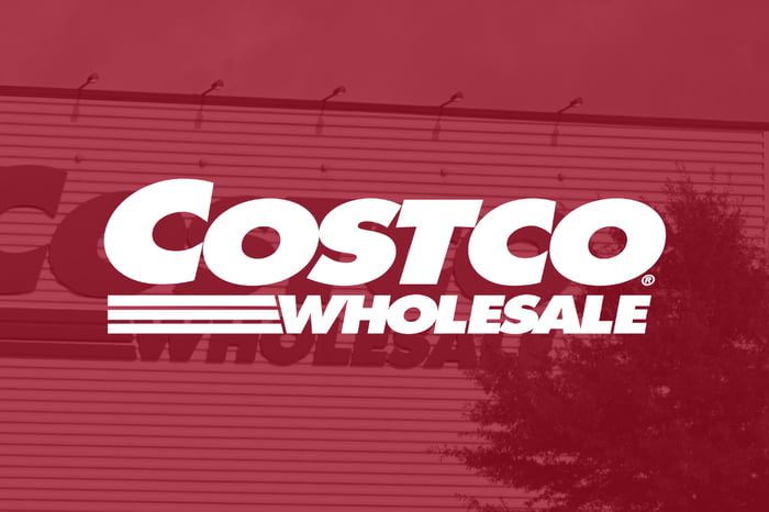 The word Costco Wholesale with a building in the background. 