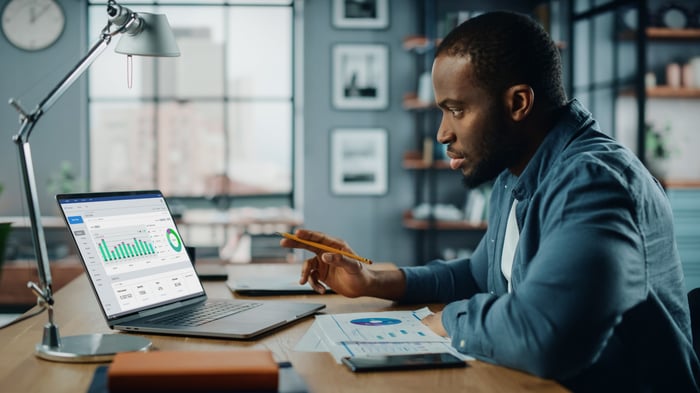 An investor seated at a desk is using a laptop.