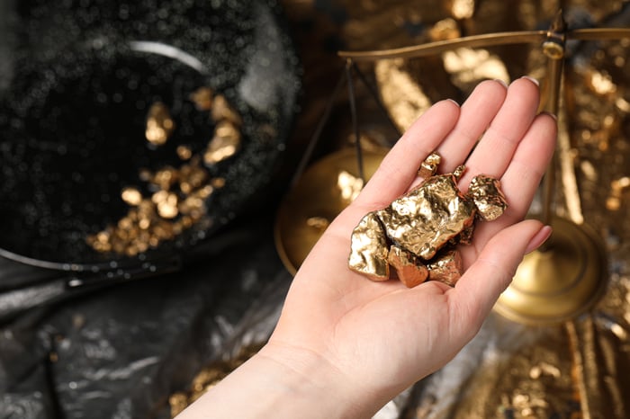 Hand of a person holding large gold nuggets.
