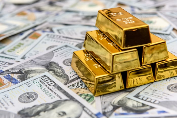 A stack of gold bars sitting on top of American cash.