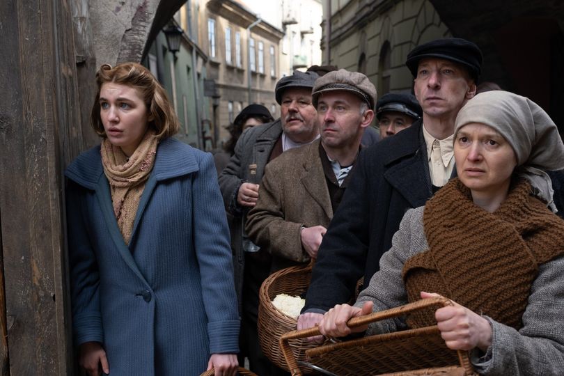 A woman stands next to a group of worried people