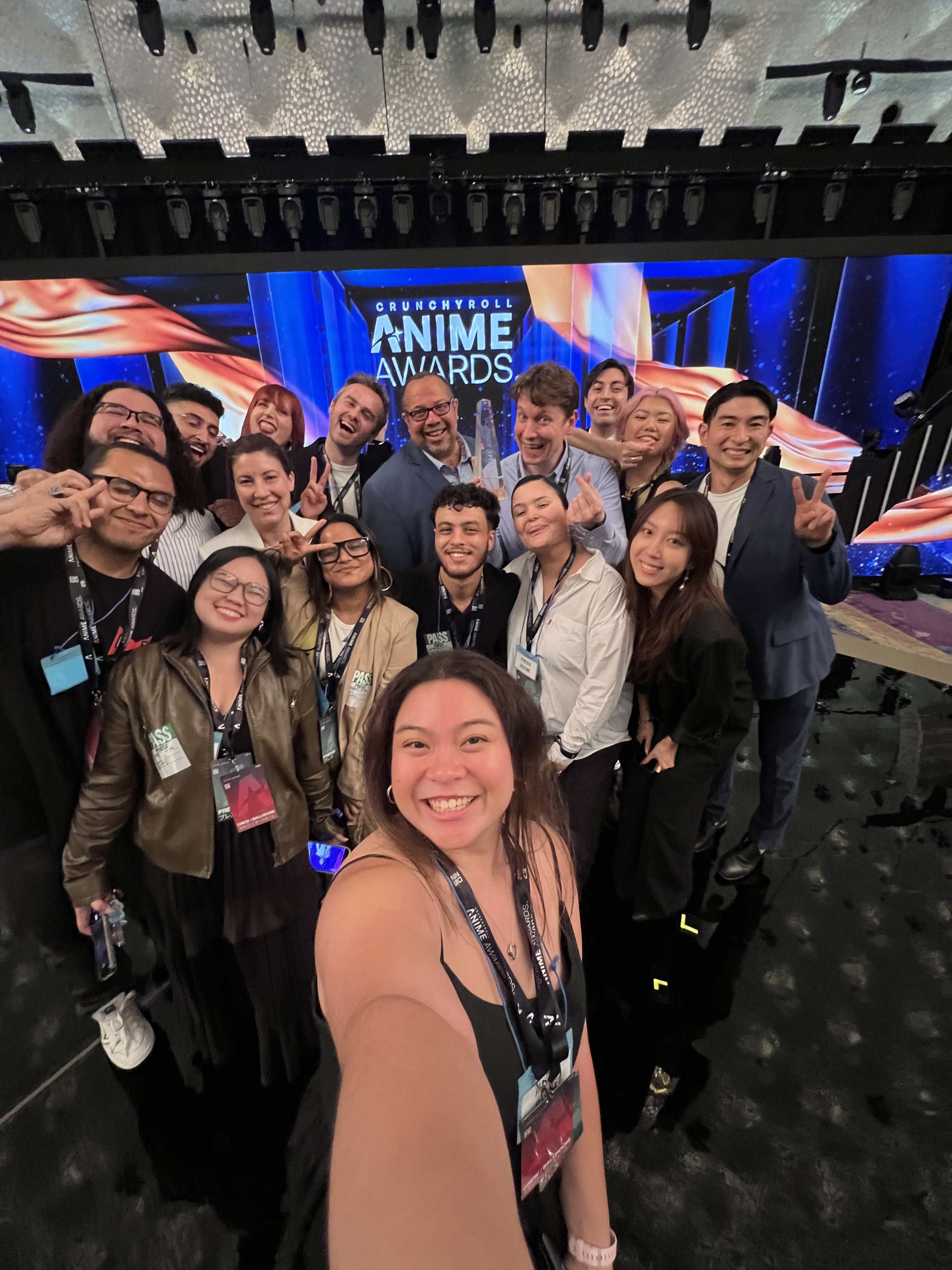 Group of people smiling and posing together at the Crunchyroll Anime Awards event stage