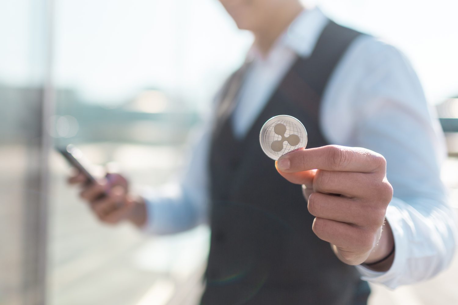 Ripple cryptocurrency coin in a young businessman hand. Disruptive blockchain technology concept and transfer of wealth.