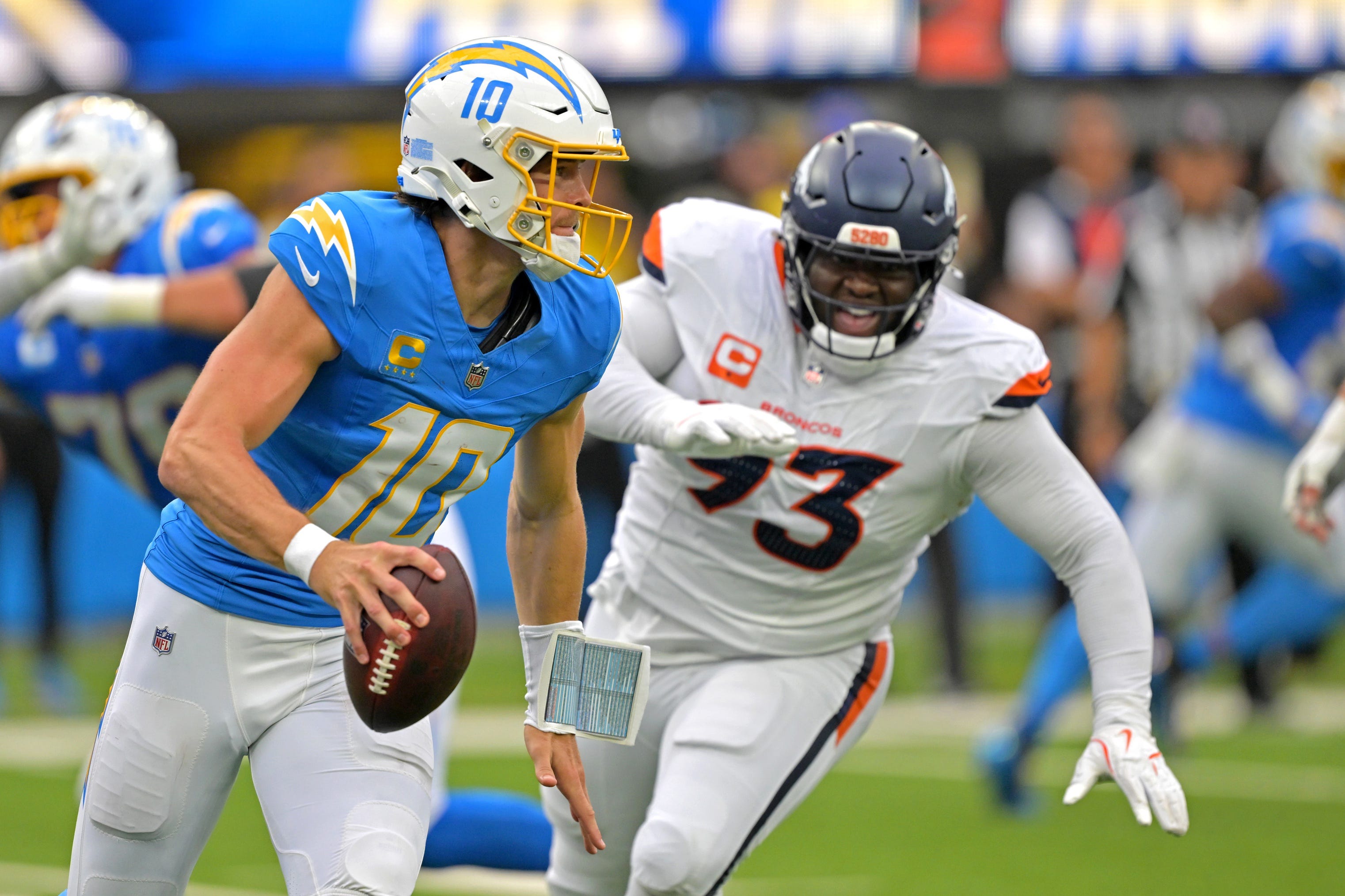 Sep 21, 2025; Inglewood, California, USA; Los Angeles Chargers quarterback Justin Herbert (10) avoids Denver Broncos defensive tackle DJ. Jones (93) as he looks to pass in the first half at SoFi Stadium. Mandatory Credit: Jayne Kamin-Oncea-Imagn Images