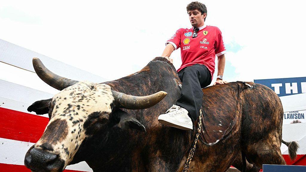 Ferrari driver Charles Leclerc riding a mechanical bull in the paddock at the 2025 US Grand Prix