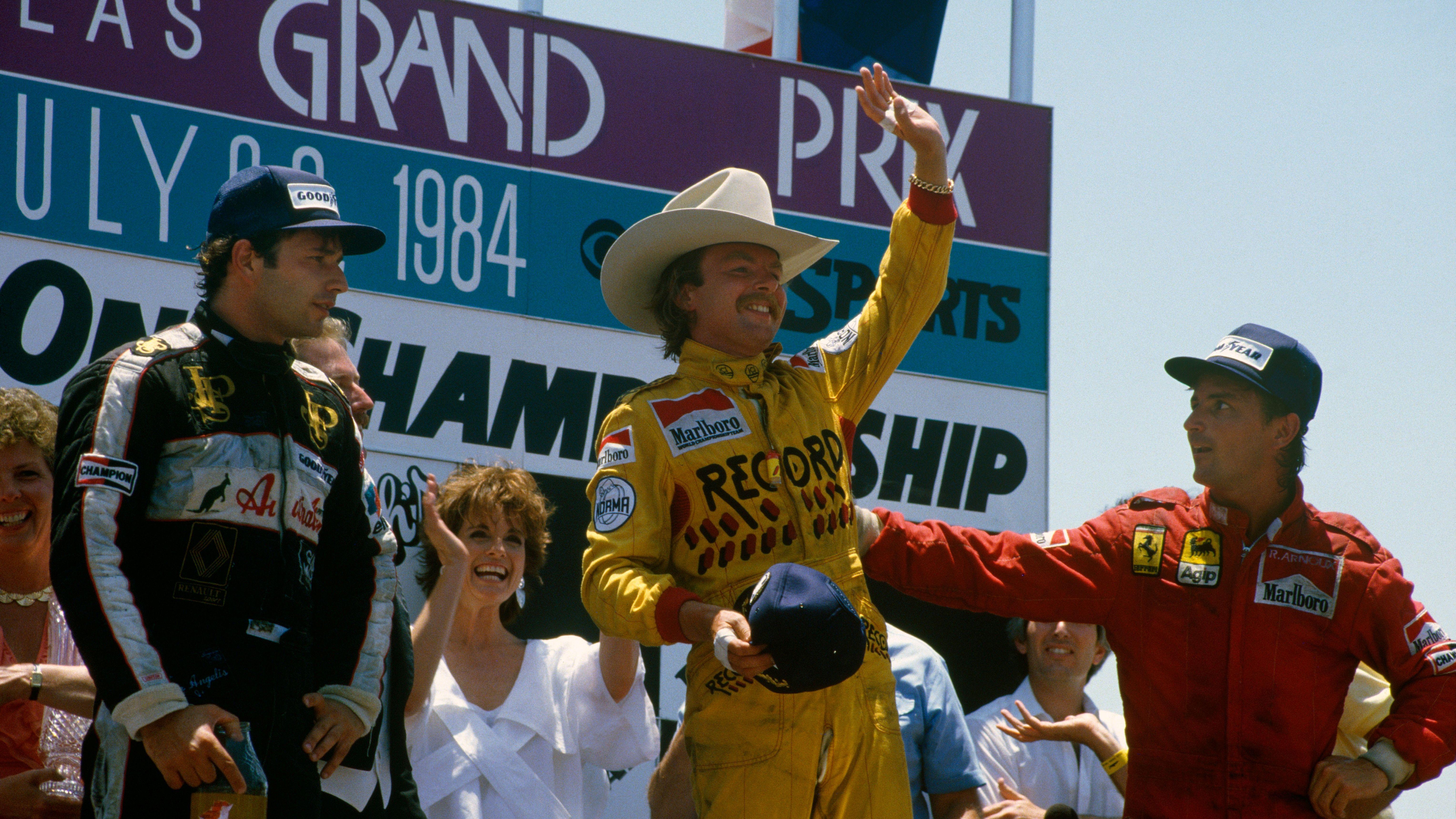 Race winner Keke Rosberg, wearing a 10-gallon hat, on the podium after the 1984 Dallas Grand Prix with Ferrari's Rene Arnoux, Lotus' Elio de Angelis and actress Linda Gray
