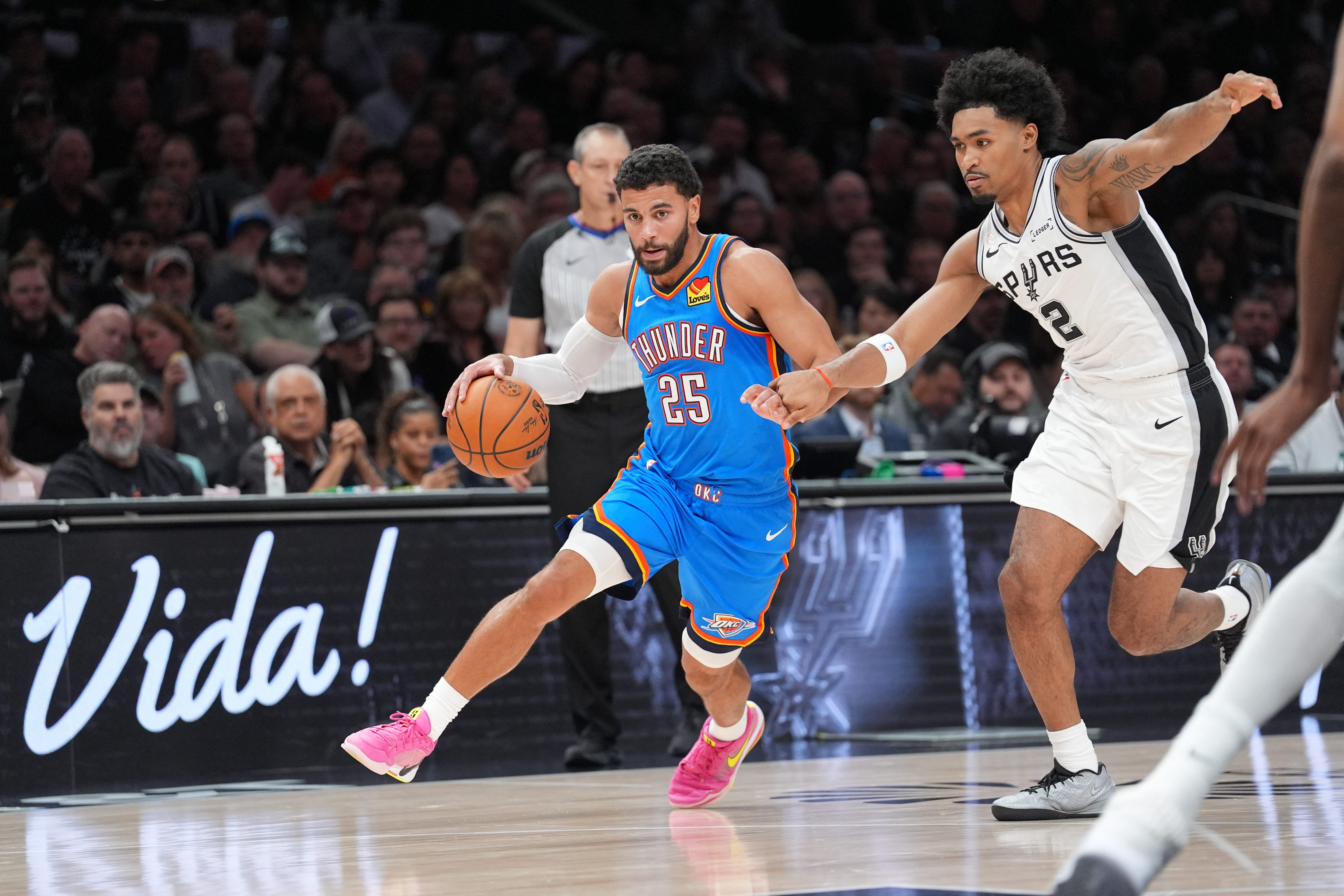 Oct 20, 2026; San Antonio, Texas, USA;  Oklahoma City Thunder guard Ajay Mitchell (25) dribbles past San Antonio Spurs guard Dylan Harper (2) in the first half Frost Bank Center.  Mandatory Credit: Daniel Dunn-Imagn Images