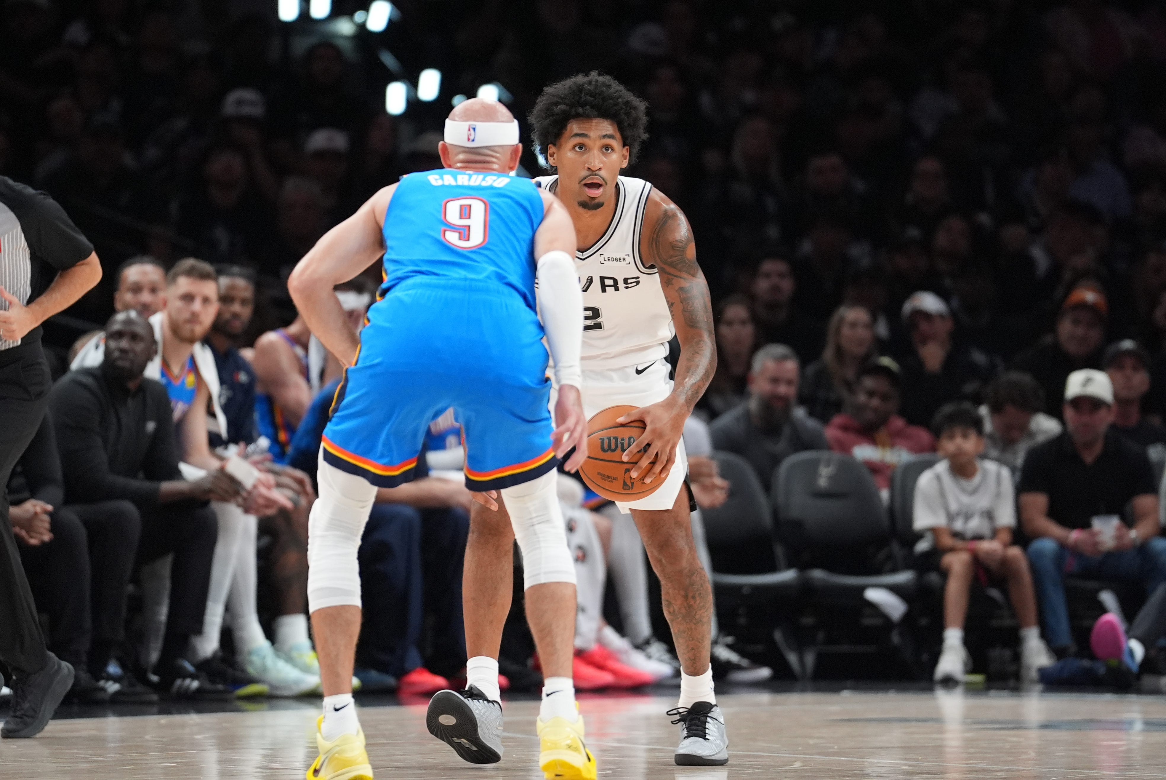 Oct 20, 2026; San Antonio, Texas, USA;  San Antonio Spurs guard Dylan Harper (2) dribbles in front of Oklahoma City Thunder guard Alex Caruso (9) in the second half at Frost Bank Center.  Mandatory Credit: Daniel Dunn-Imagn Images