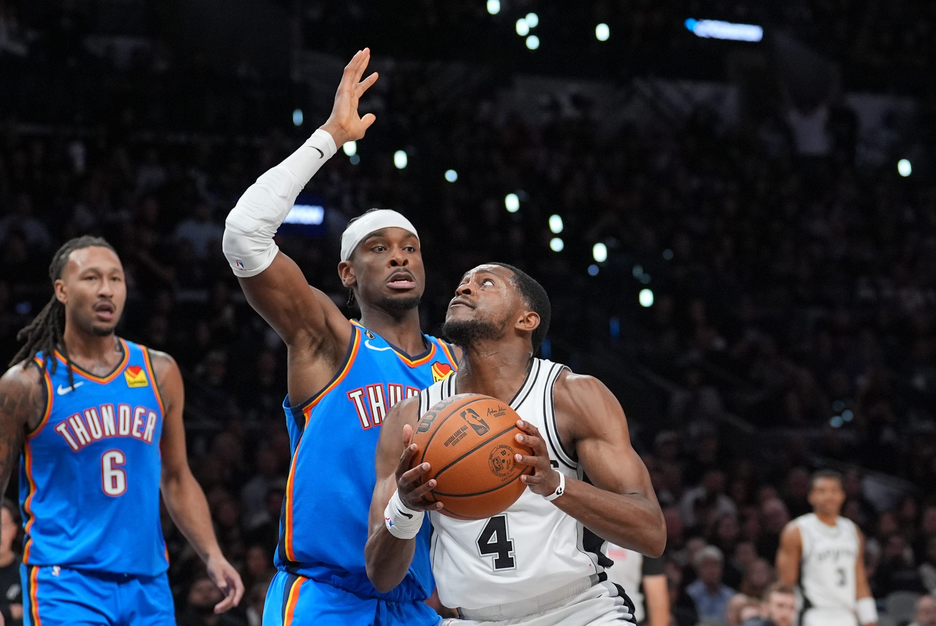 Oct 20, 2026; San Antonio, Texas, USA;  San Antonio Spurs guard De'aaron Fox (4) looks to shoot against Oklahoma City Thunder guard Shai Gilgeous-Alexander (2) in the second half at Frost Bank Center.  Mandatory Credit: Daniel Dunn-Imagn Images