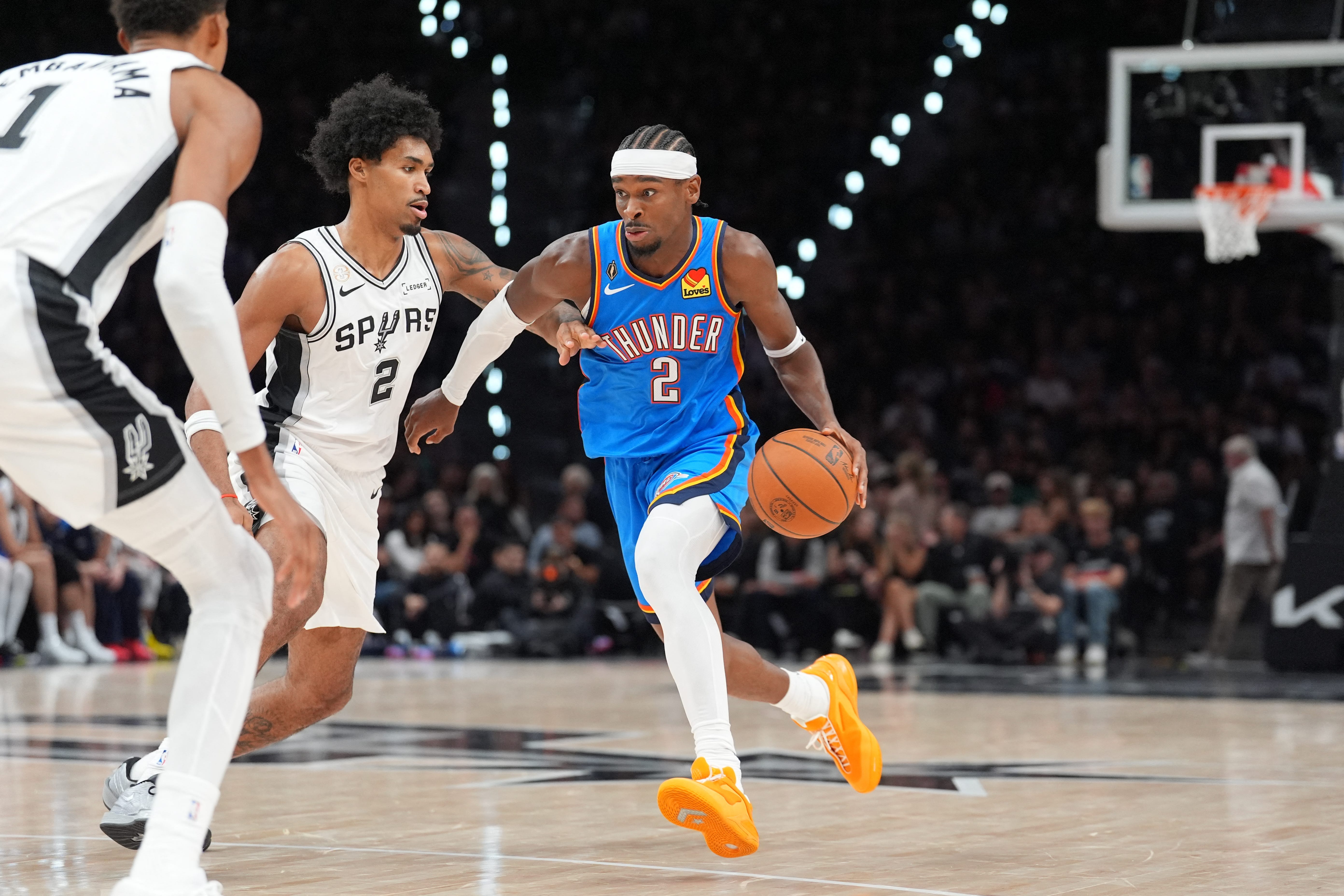 Oct 20, 2026; San Antonio, Texas, USA;  Oklahoma City Thunder guard Shai Gilgeous-Alexander (2) dribbles against San Antonio Spurs guard Dylan Harper (2) in the first half at Frost Bank Center.  Mandatory Credit: Daniel Dunn-Imagn Images
