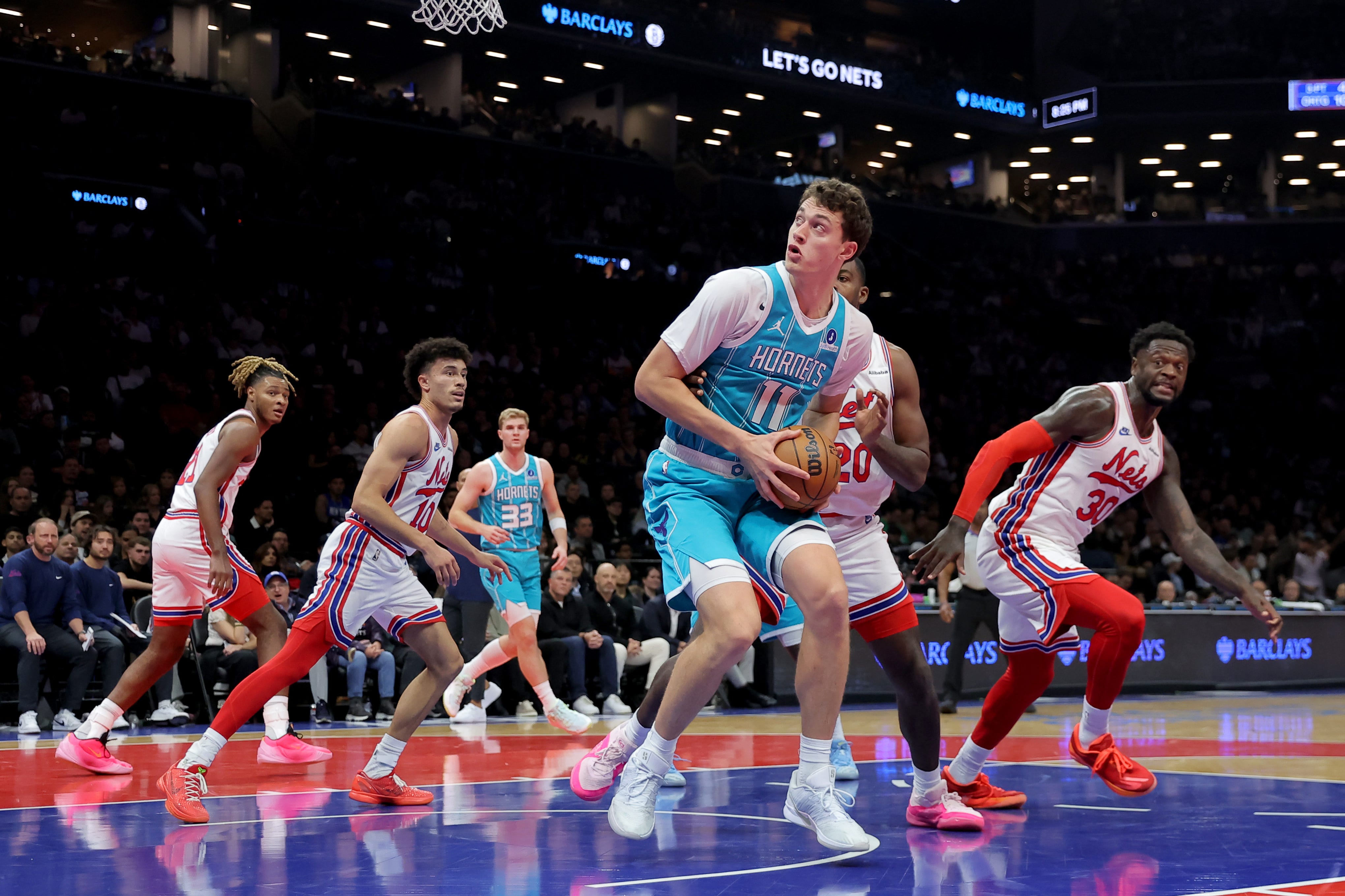 Oct 21, 2026; Brooklyn, New York, USA; Charlotte Hornets center Ryan Kalkbrenner (11) looks to shoot the ball against Brooklyn Nets forward Noah Clowney (21) and guard Nolan Traore (10) and center Day'ron Sharpe (20) and forward Julius Randle (30) during the second quarter at Barclays Center. Mandatory Credit: Brad Penner-Imagn Images